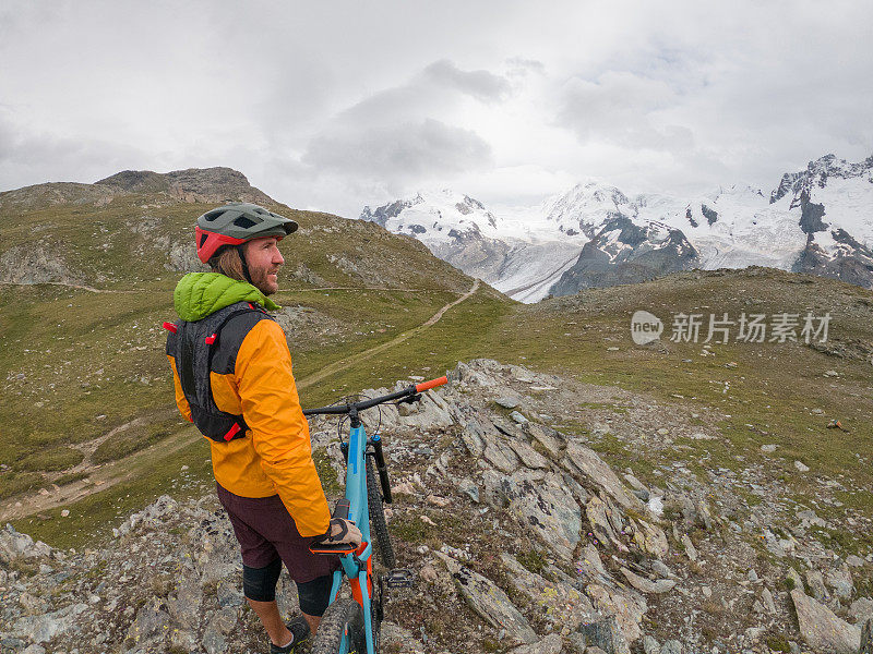 男性山地自行车爱好者欣赏风景，土路，远处的冰川