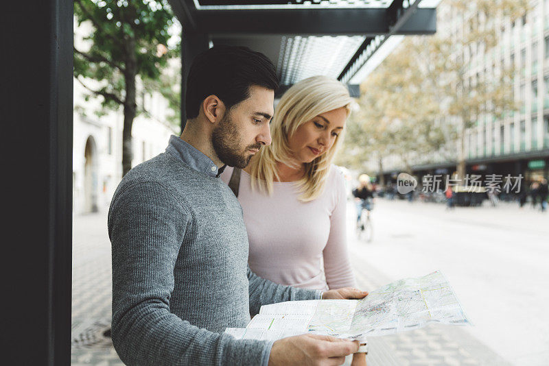 一对快乐的旅游夫妇在一个新的城市，用城市地图导航