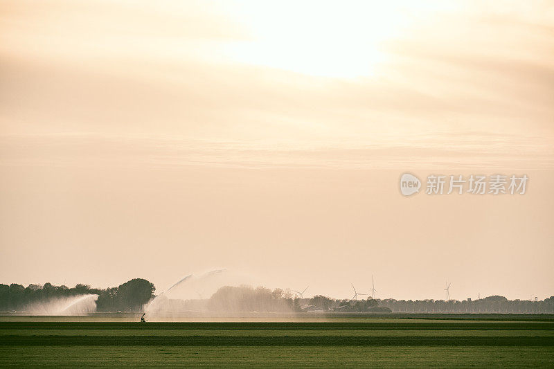 在干燥温暖的春日，喷灌机在田间喷水。