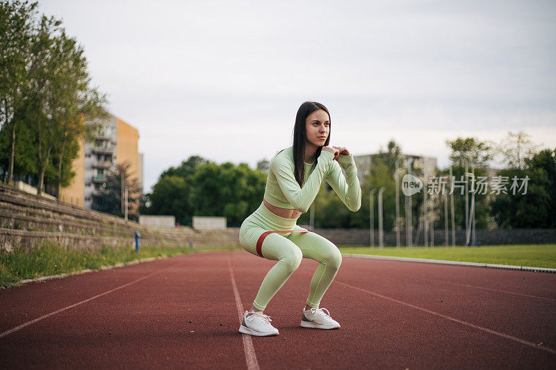 美丽的年轻女子做蹲坐健身环带