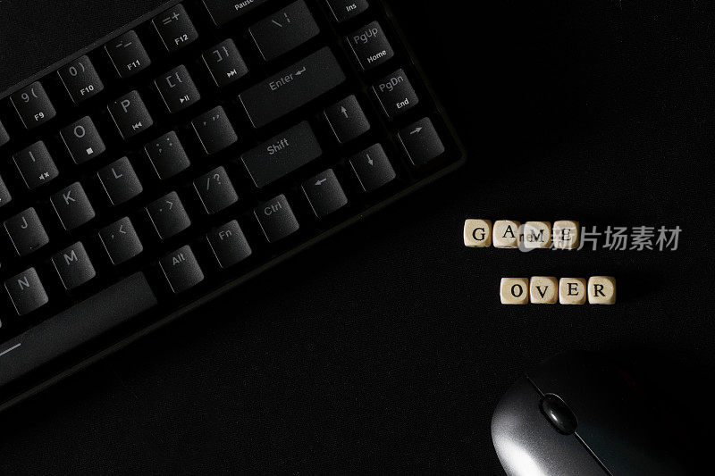 游戏结束后旁边的铭文是黑色的机械键盘和黑色的电脑鼠标。赌博和宿命的结局。悲剧和悲观。游戏结束。