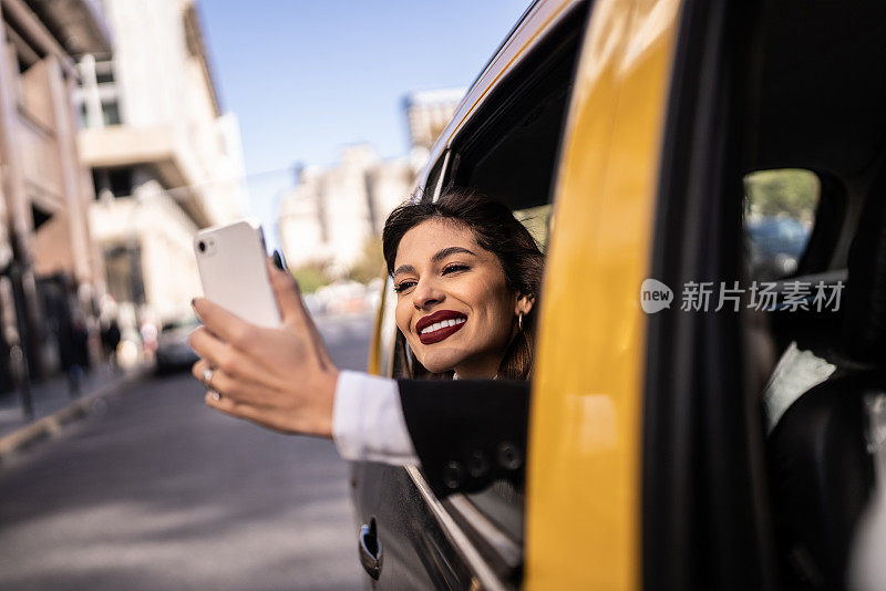 在出租车上用手机拍摄风景的年轻女子