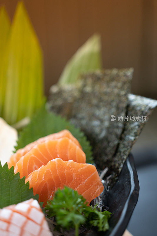 新鲜切片三文鱼刺身配干海带，盛于碗中，放在桌上。