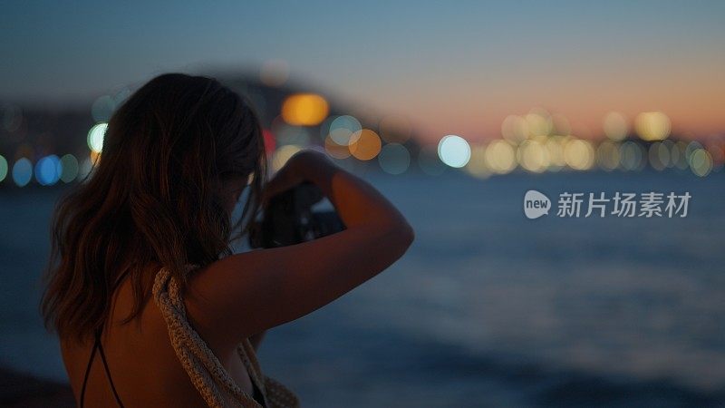年轻女游客在旅行中拍摄海景照片和视频