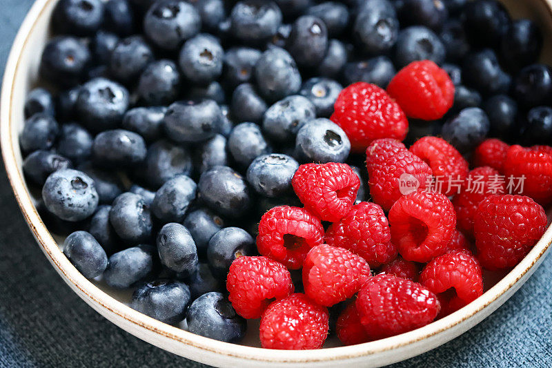 新鲜的树莓和蓝莓在碗里。健康的零食。浆果做甜点。特写镜头。