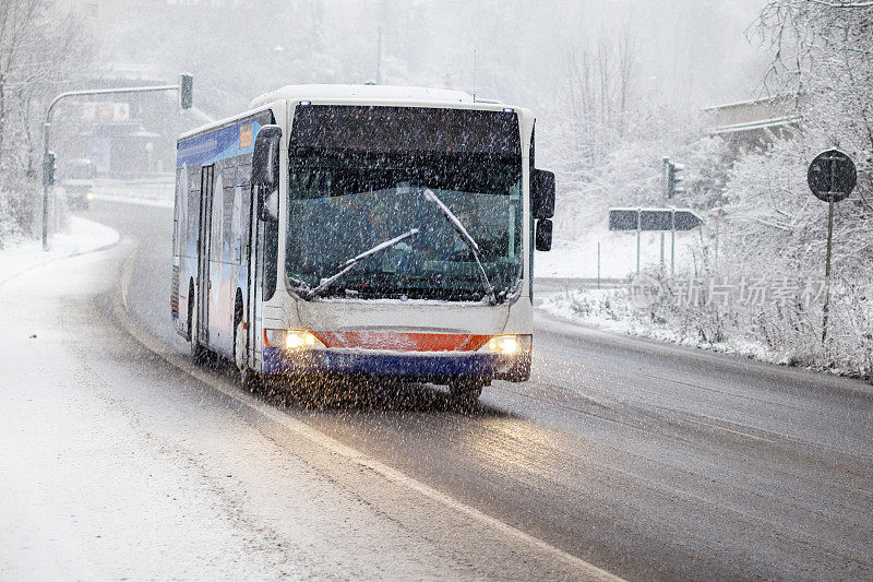 公路上的公共汽车在冬天的降雪中缓慢行驶