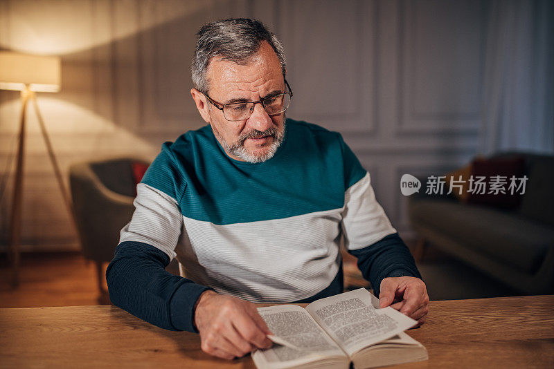 一位孤独的老人在他的家庭办公室里看书