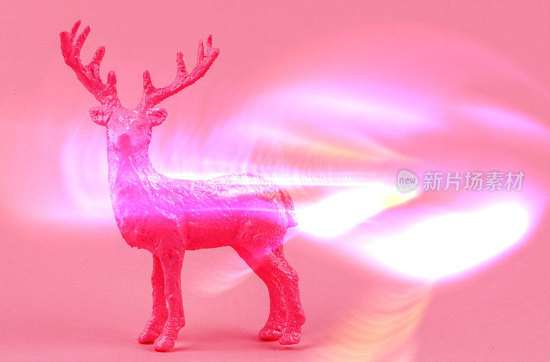 节日的圣诞背景。粉红色的鹿在粉红色的背景与闪闪发光的光学效果。