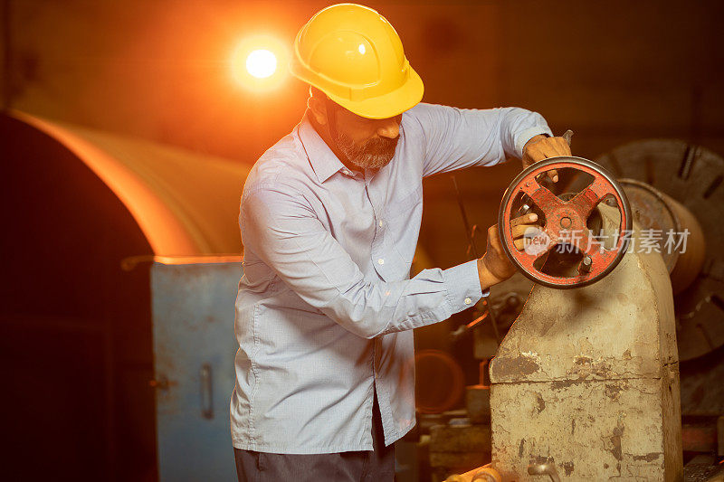 戴着黄色安全帽的印度男子在工业工厂的机器上工作，机械工人，技术印度。