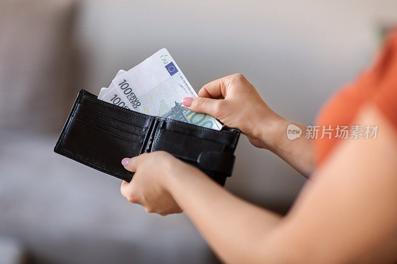 一名年轻女子在家从钱包里拿出钱的特写镜头