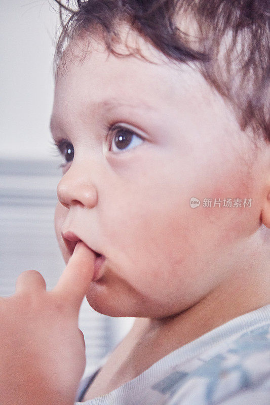 一个嘴巴含着手指的小孩的大头照