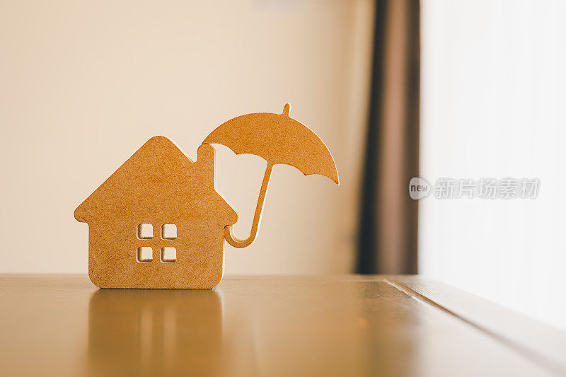 木屋模型和不动产保险构思，个人手持小雨伞和样板房。房屋灭失和火灾保险，建筑火灾保险概念。