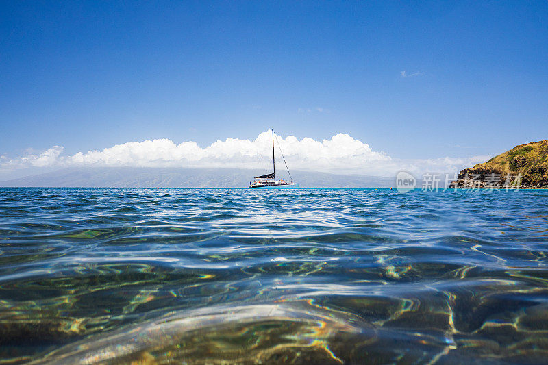 在一个阳光明媚的日子里，帆船停泊在夏威夷平静的海湾里