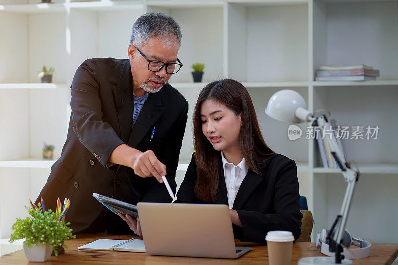 一个亚洲商人和女经理的肖像使用笔记本电脑和平板电脑分析统计数据，贸易数据，营销