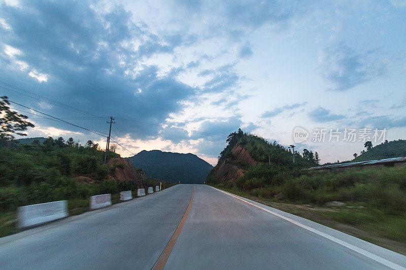 乡村高速公路动态模糊拍摄与汽车钻机接近黄昏