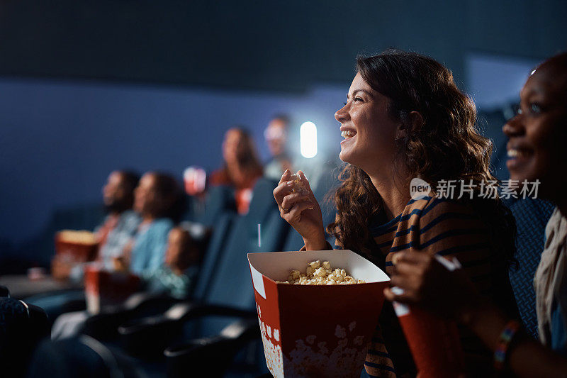 快乐的女人在电影院享受电影放映。