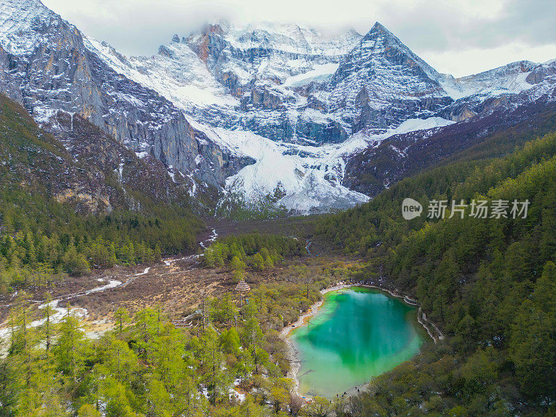 中国亚丁自然保护区无人机鸟瞰图。白雪皑皑的陈若芝风景如画，四周环绕着常绿的树木和湖泊