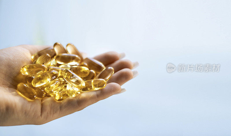 特写药物黄色透明丸，欧米茄3鱼油胶囊，维生素d。许多黄色透明胶囊在手特写。健康、维生素和药物的概念