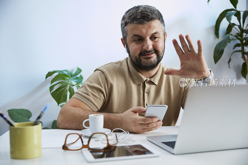 一个年轻人在他的家庭办公室里对着电脑说话