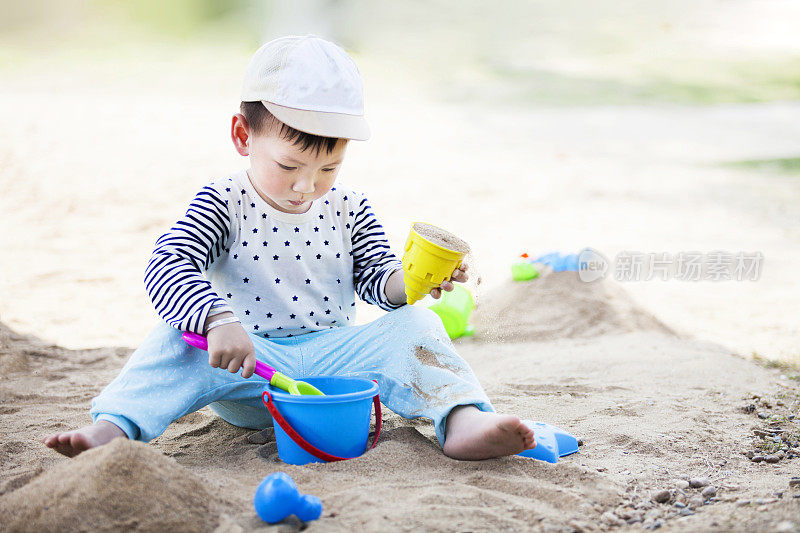 可爱的小男孩在热带海滩上玩海滩玩具