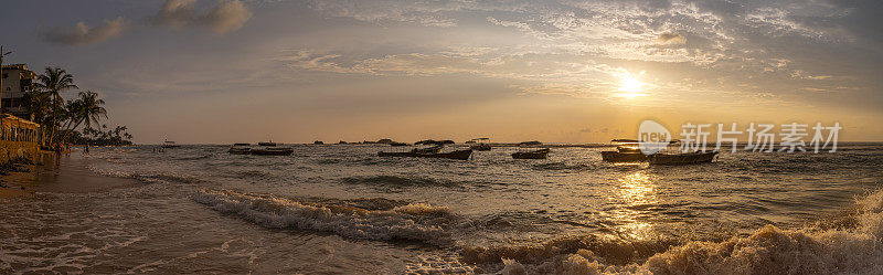 日落时海上的小船。斯里兰卡Hikkaduwa海滩全景。