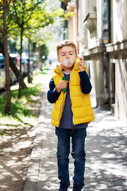 小男孩在户外用泡泡棒吹泡泡。