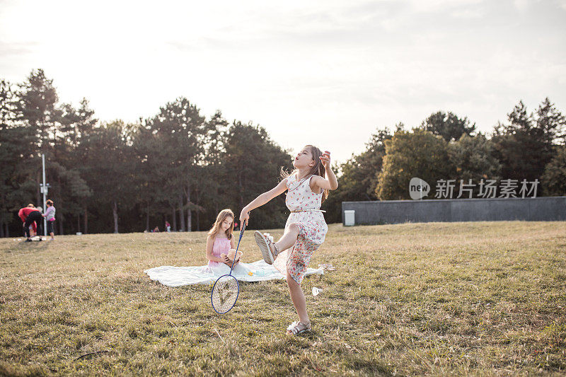 漂亮的女孩穿着夏装在公园里打羽毛球