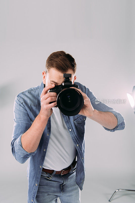 摄影师在照相馆的泛光灯旁用数码相机拍照
