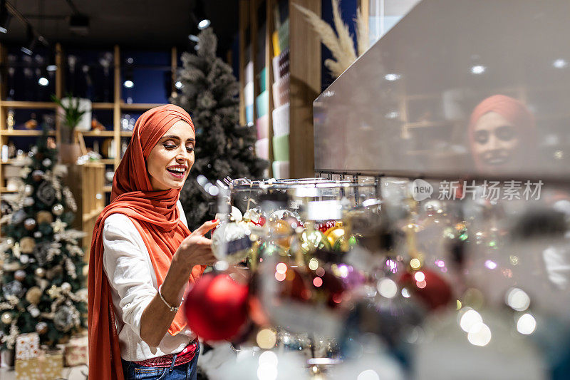 迷人的穆斯林女士拿装饰圣诞树