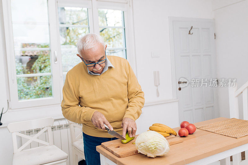 一位老人正在切菜做午餐