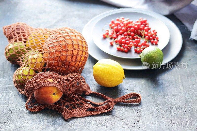 新鲜的柑橘类水果装在一个由天然材料制成的袋子里放在厨房的桌子上