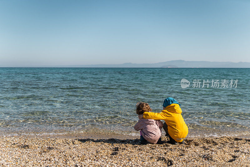 弟弟和妹妹在寒冷的日子一起在海滩上度过时光