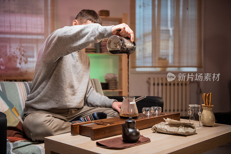 在家里冲泡正宗日本茶的过程。一个男人把热水倒进一个装满干茶叶的碗里