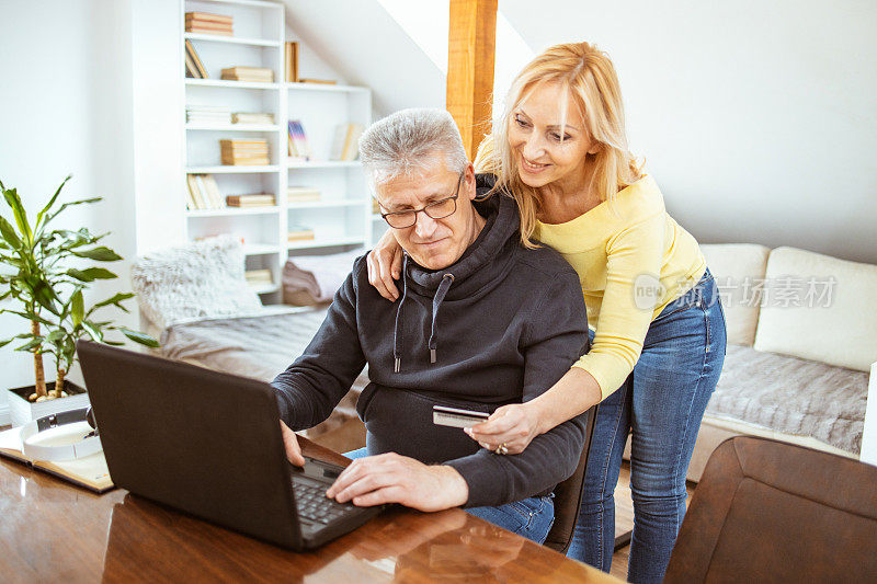 一对成熟的快乐夫妇用笔记本电脑在网上购物