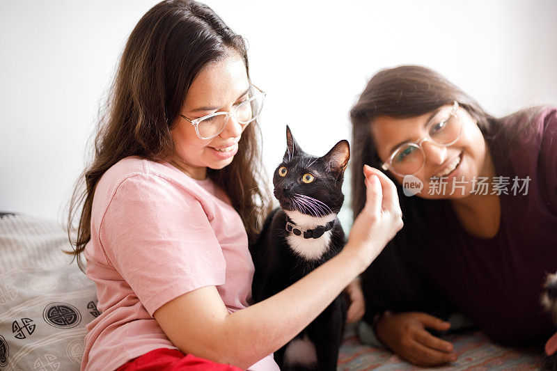 黑猫和两个年轻女人坐在床上的肖像