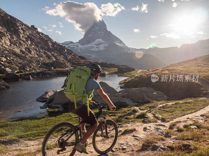 一名山地自行车手沿着马特洪山下的里费尔湖骑行