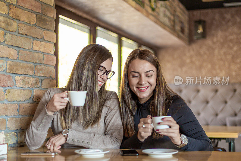 两个开心的女人在咖啡馆里喝咖啡。