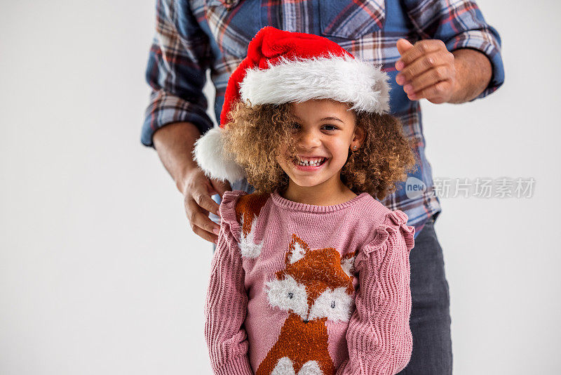 父亲给他顽皮的女儿戴上圣诞帽