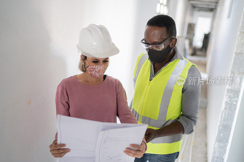 工程师和建筑工人拿着图纸讨论施工——戴着防护口罩