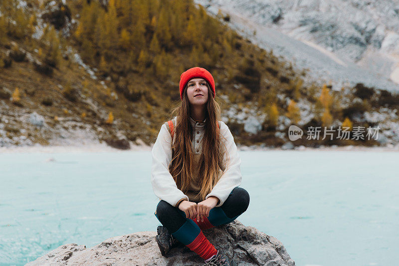 快乐的女旅行者坐在岩石上享受风景的tuquouise冻结高山湖在阿尔卑斯山