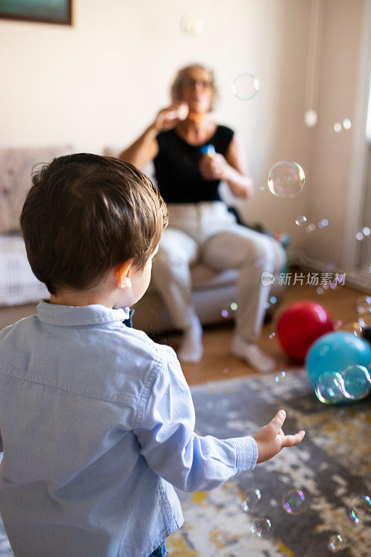 小男孩和他的祖母在一起玩，吹泡泡