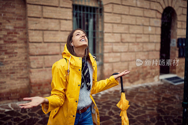 一个小女孩正在享受落在她身上的雨滴。走,雨,城市