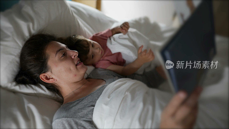 睡前，妈妈抱着孩子躺在床上读睡前故事