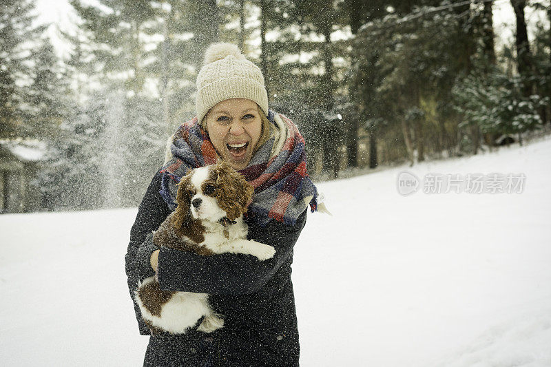 在雪地里，一名女子抱着她的查理骑士猎犬