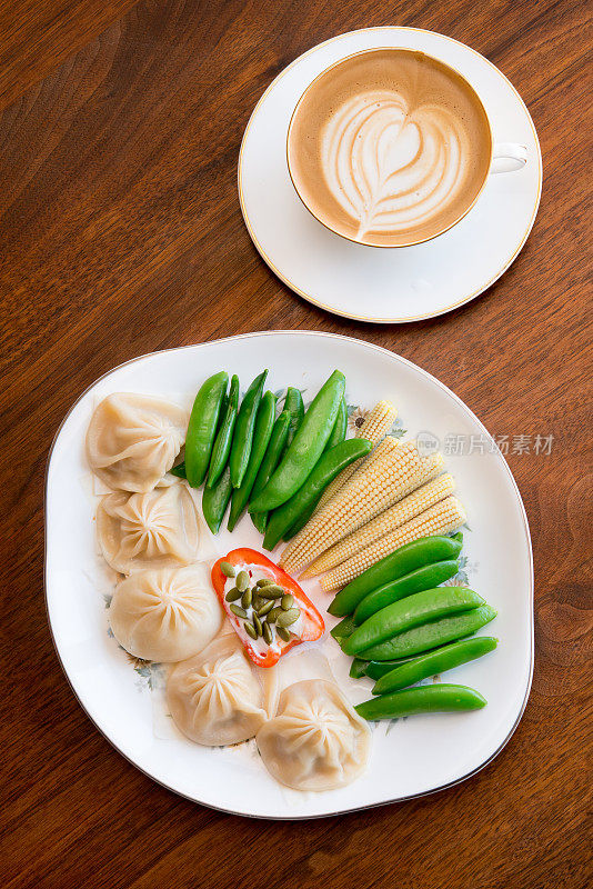 平衡的低碳水化合物膳食——蒸鸡肉、肉汤、饺子和鲜亮颜色的焯过的蔬菜，再配上一杯白咖啡