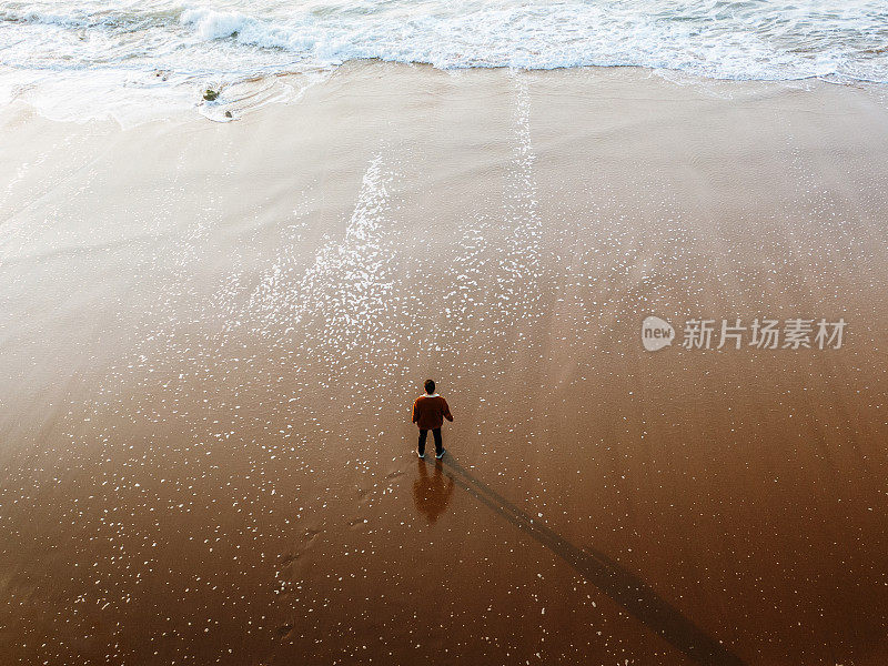 日落时站在海滩上的人