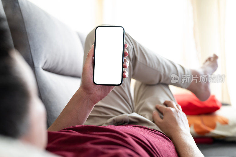 成年男子在客厅沙发上使用黑白屏幕的智能手机