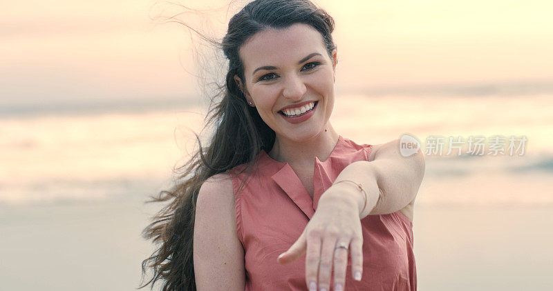 美丽快乐的年轻女子在海滩上炫耀她的订婚戒指。微笑的女人求婚后，展示她的手和戒指