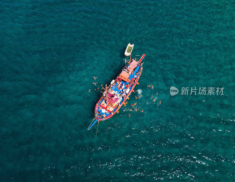 在炎热的夏天，红色游轮的鸟瞰图。俯视图的人正在船周围游泳