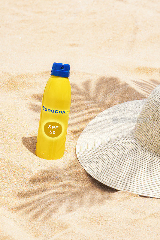 防晒系数50的防晒喷雾瓶戴着遮阳帽躺在沙滩上